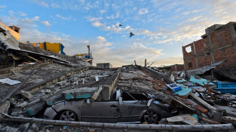 Calle del centro urbano de Manabí con edificios colapsados sobre la vía y un automóvil sepultado bajo los escombros tras el terremoto del 16 de abril de 2016