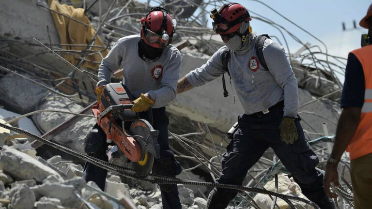 Dos rescatistas cortan varillas de acero entre los escombros de una estructura colapsada durante las labores de búsqueda
