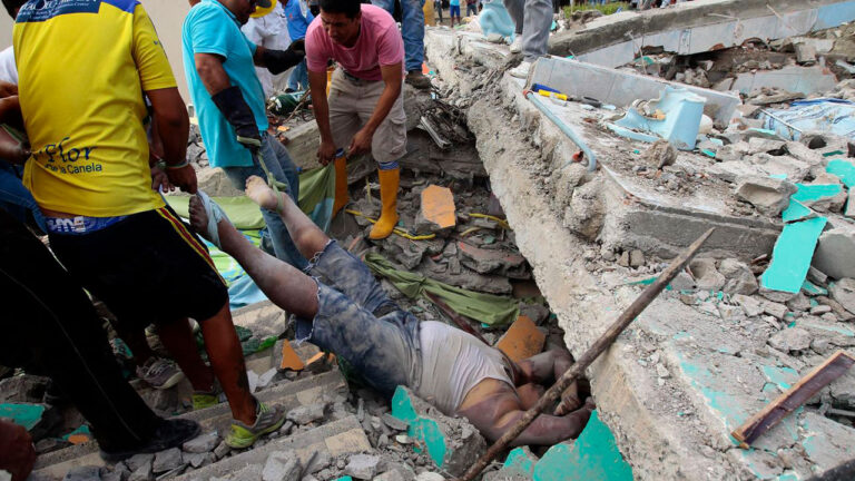 Vecinos y voluntarios retiran a una persona de entre los escombros de una edificación colapsada