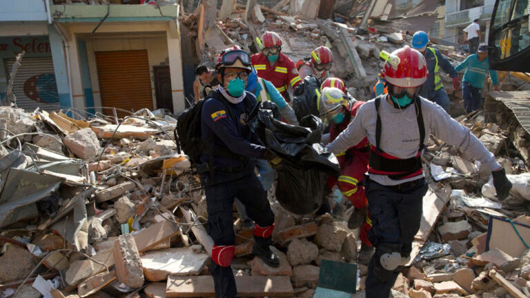 Cuerpos de socorro y personal médico trasladan a una persona sobre los escombros de un edificio derrumbado