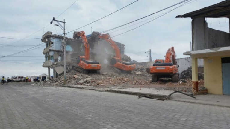Demolición controlada de un edificio afectado por el terremoto, con tres excavadoras trabajando sobre la estructura
