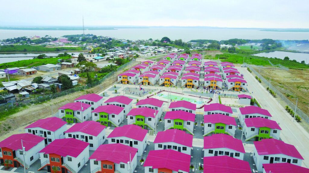 Vista aérea del conjunto de viviendas de Chamanga junto al estuario, con casas de techo rojo, cancha deportiva y juegos infantiles