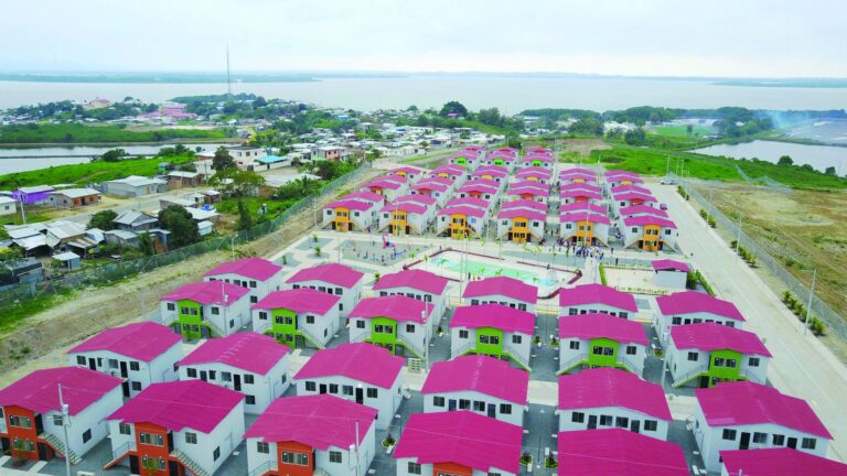 Vista aérea del conjunto de viviendas de Chamanga junto al estuario, con casas de techo rojo, cancha deportiva y juegos infantiles