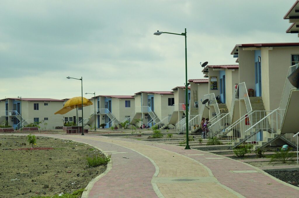 Calle interior del conjunto habitacional de Jaramijó, con viviendas de dos plantas, escaleras exteriores y aceras terminadas