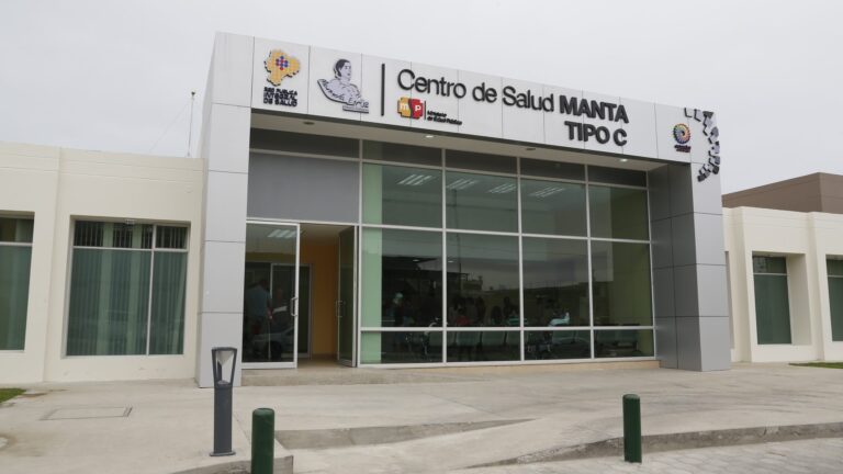 Fachada del Centro de Salud Manta Tipo C terminado, con ingreso acristalado y sala de espera ocupada por pacientes
