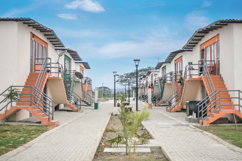 Pasaje peatonal de Ciudad Jardín en Pedernales, con viviendas de dos plantas, escaleras naranjas y luminarias