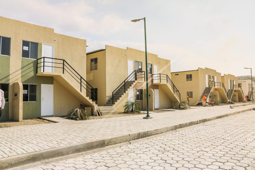 Calle adoquinada de la ciudadela El Guabito, con viviendas de dos plantas y obreros terminando los acabados