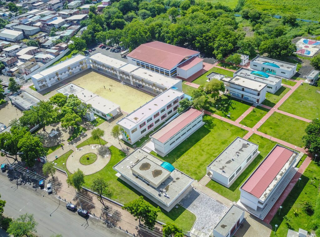 Vista aérea del complejo educativo Olmedo terminado, con bloques de aulas alrededor del patio central, coliseo y áreas verdes