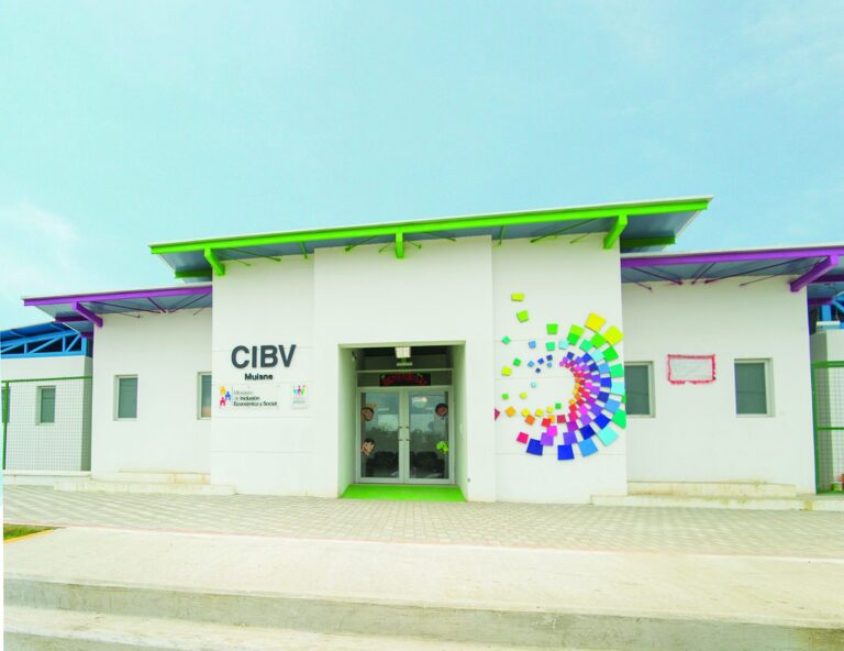 Fachada del Centro Infantil del Buen Vivir de Muisne, con mural de colores, aleros verdes y morados, y cartel de bienvenida