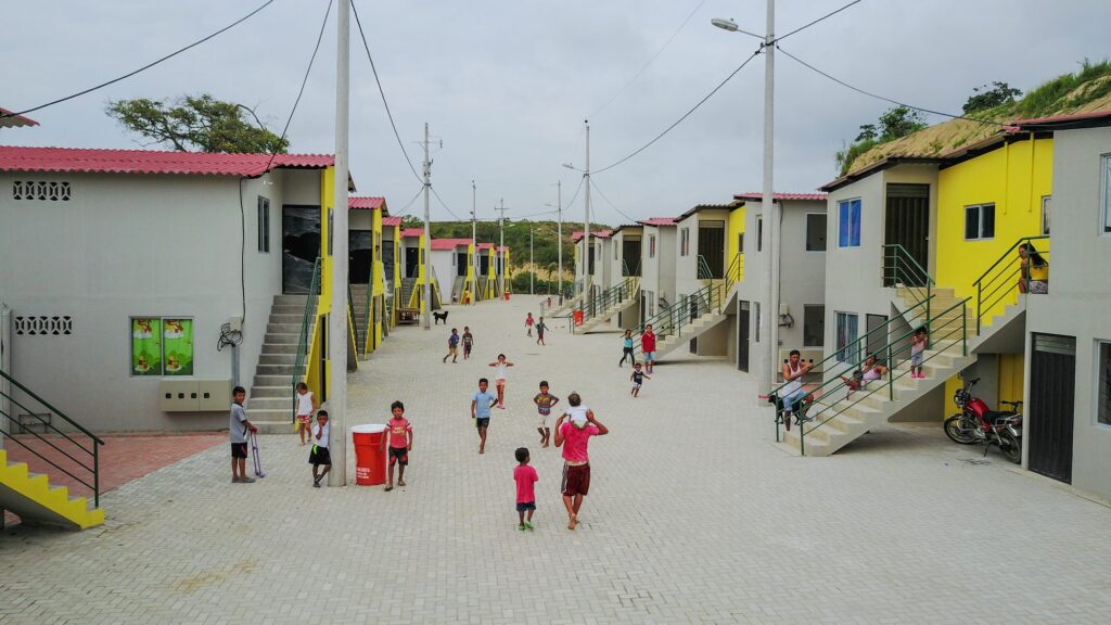 Pasaje peatonal del conjunto habitacional Nuevo Portete con niños jugando frente a viviendas de dos plantas ya habitadas