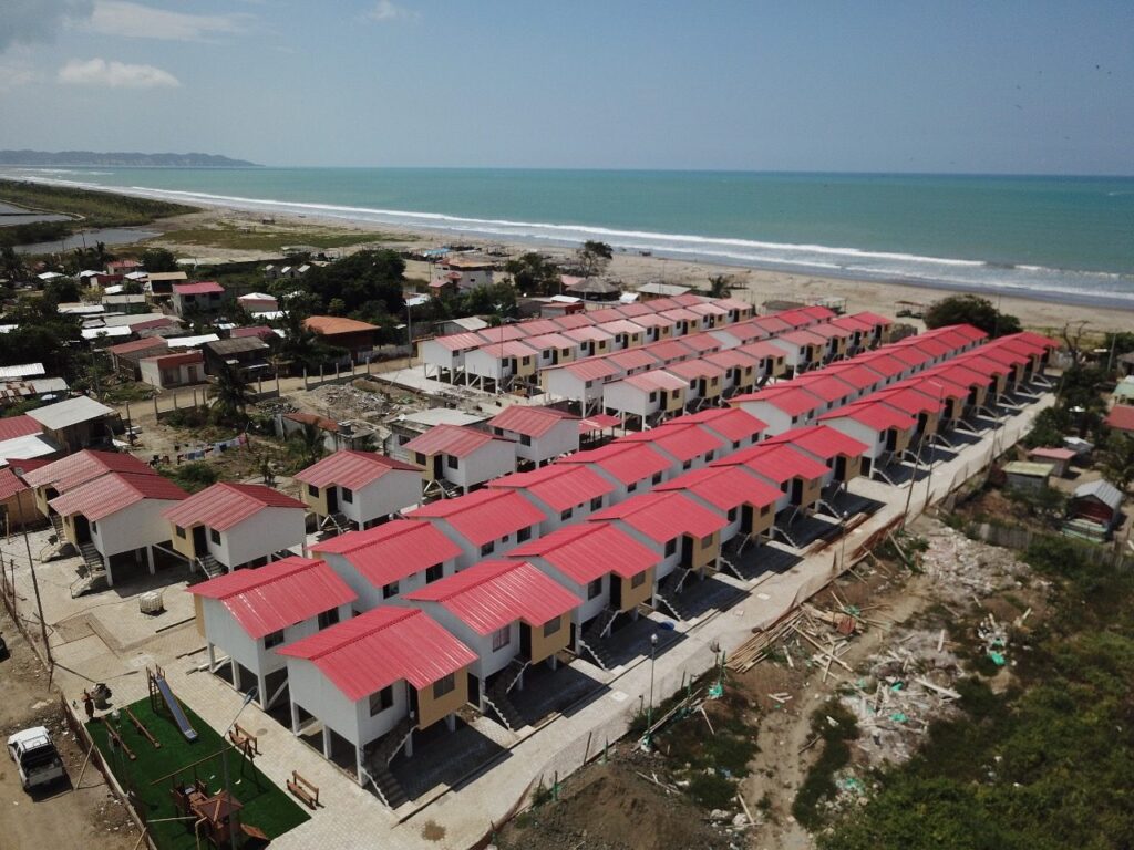 Vista aérea de las viviendas de Don Juan, Jama, alineadas frente al mar con juegos infantiles y aceras terminadas